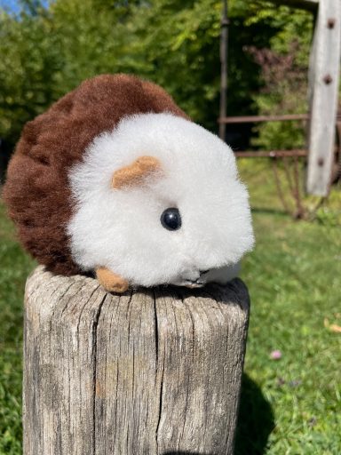 Stofftier aus Alpakawolle - Spielzeug Gege Stress Stofftier in Form eines Igel mit braunem und weißem Fell auf einem Pfosten.